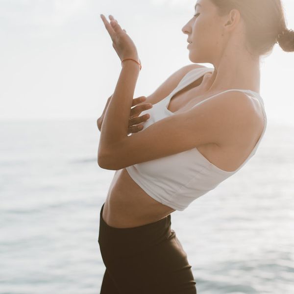 Silhouette of a man stretching against a sunrise, symbolizing balance and energy.